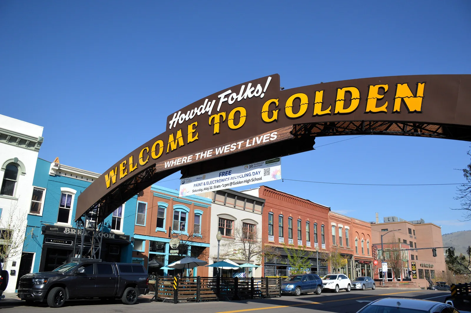 The Welcome to Golden arch over Washington Avenue, with brick storefronts and a clear blue sky